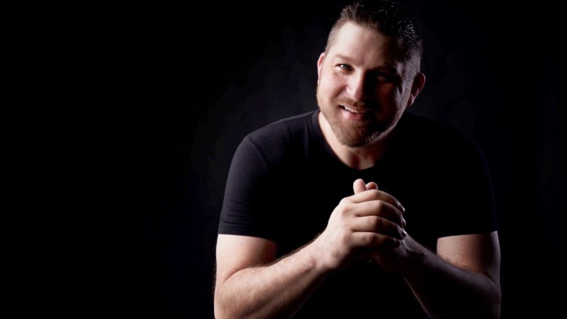 Patch Baker sitting with black shirt and black background